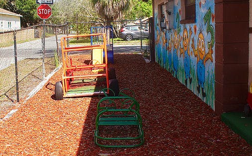 Playground with wood chips, a colorful mural, and a stop sign