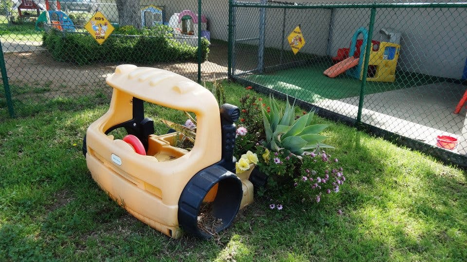 Toy car on grass next to a fenced play area