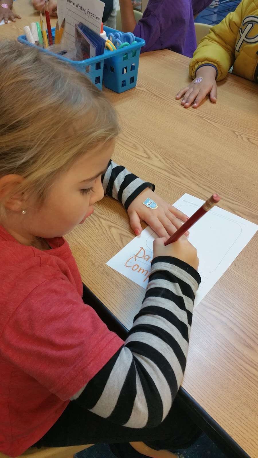 Child writing on paper with a pencil at a table