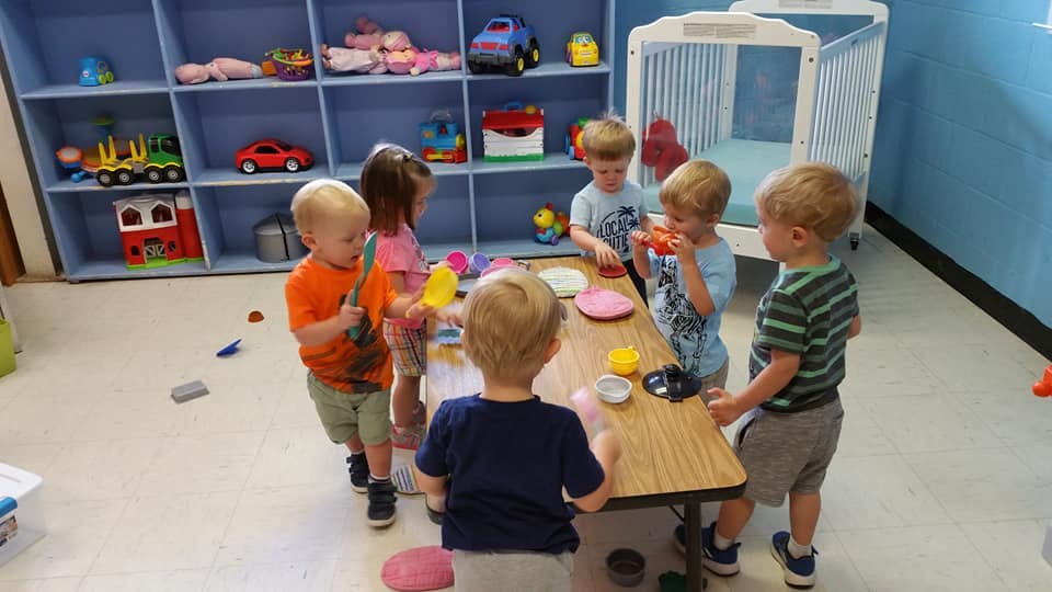 Children playing around a small table in a classroom