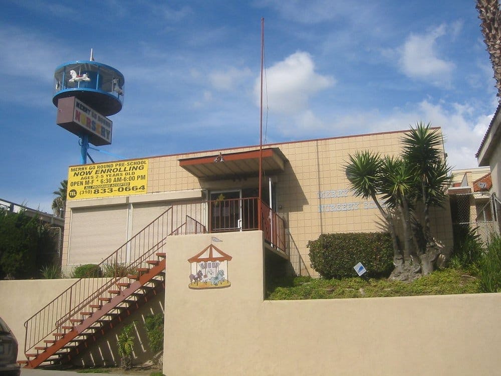 Building exterior with stairs leading to an entrance and a sign with a carousel sign
