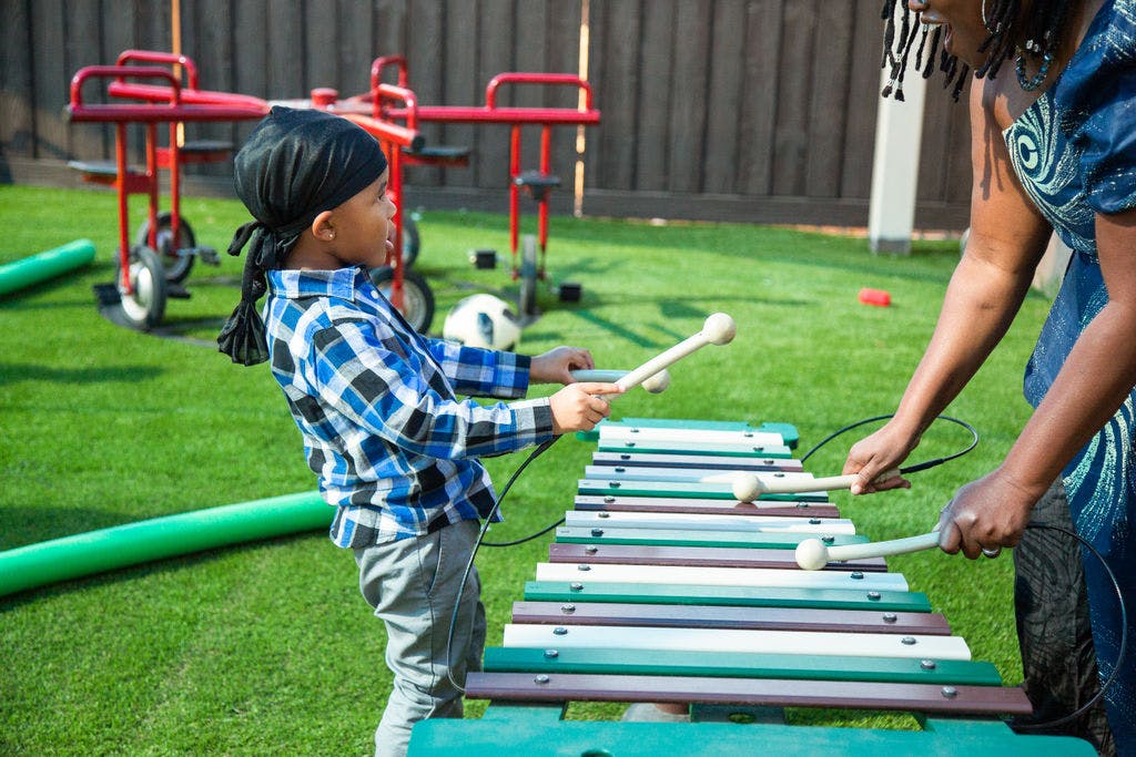Child and adult playing outdoor xylophone