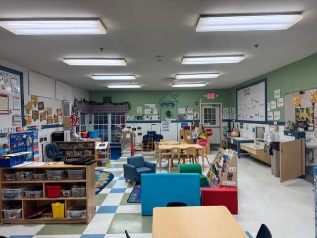 An empty early childhood classroom with multiple learning stations and tables