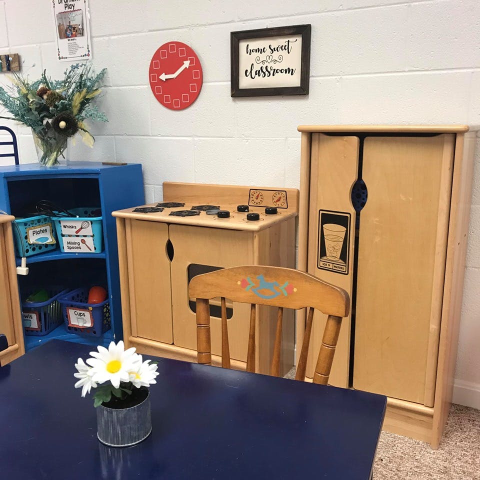 Play kitchen set with a stove, refrigerator, and a small chair