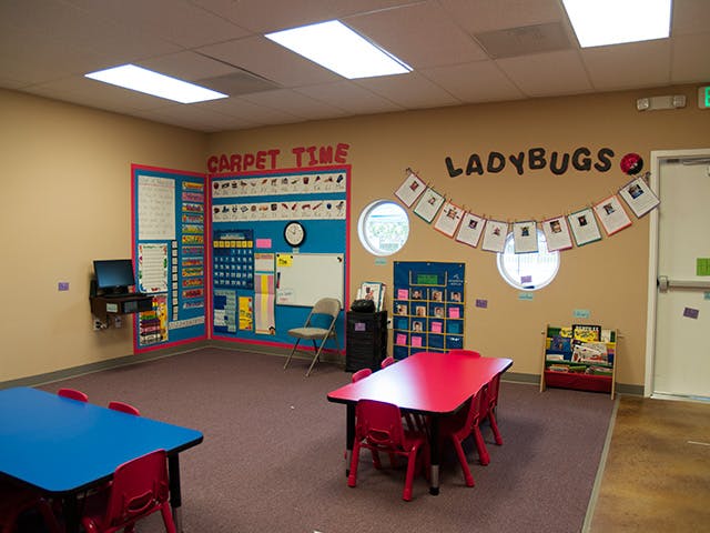 Classroom with red and blue tables, bulletin boards, and a sign that says "LADYBUGS"