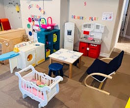 Playroom with toy kitchen, laundry set, table, and crib