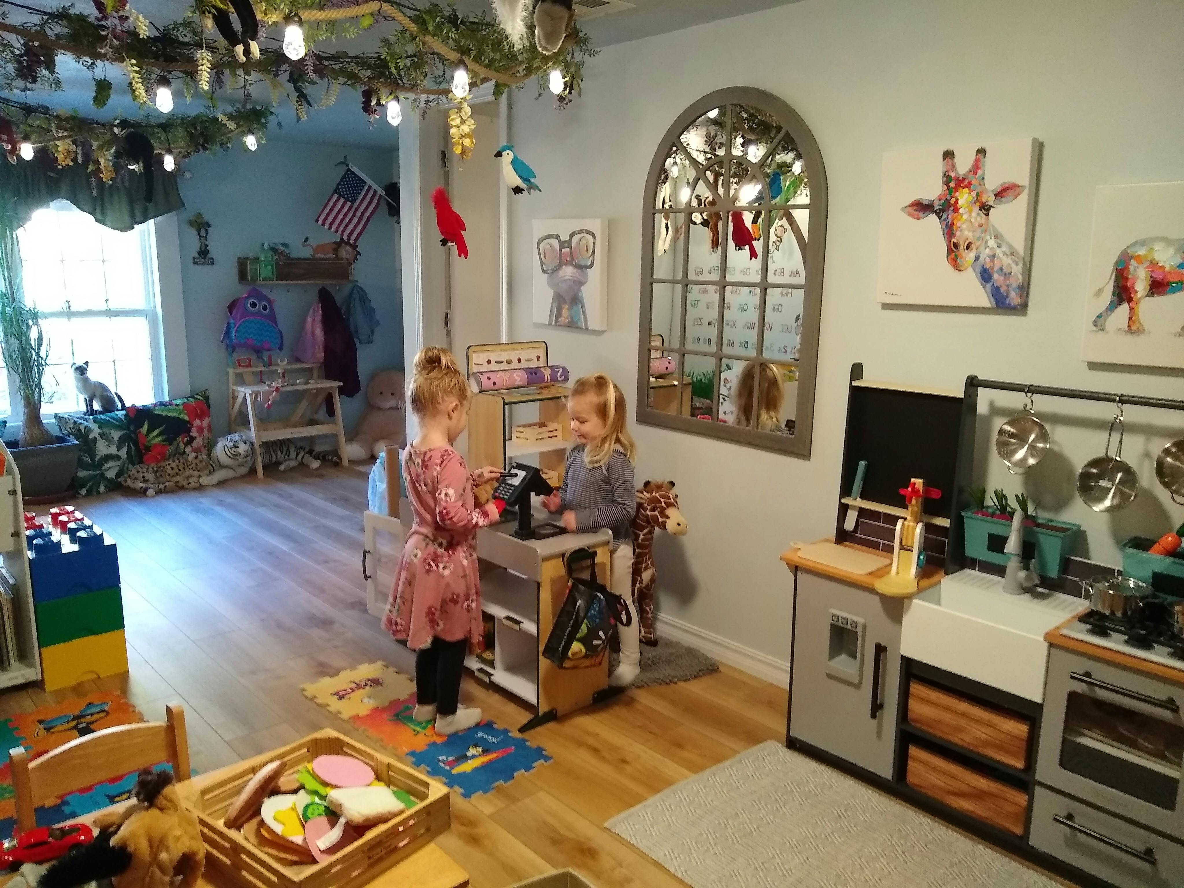 Two children playing with a toy kitchen set in a playroom