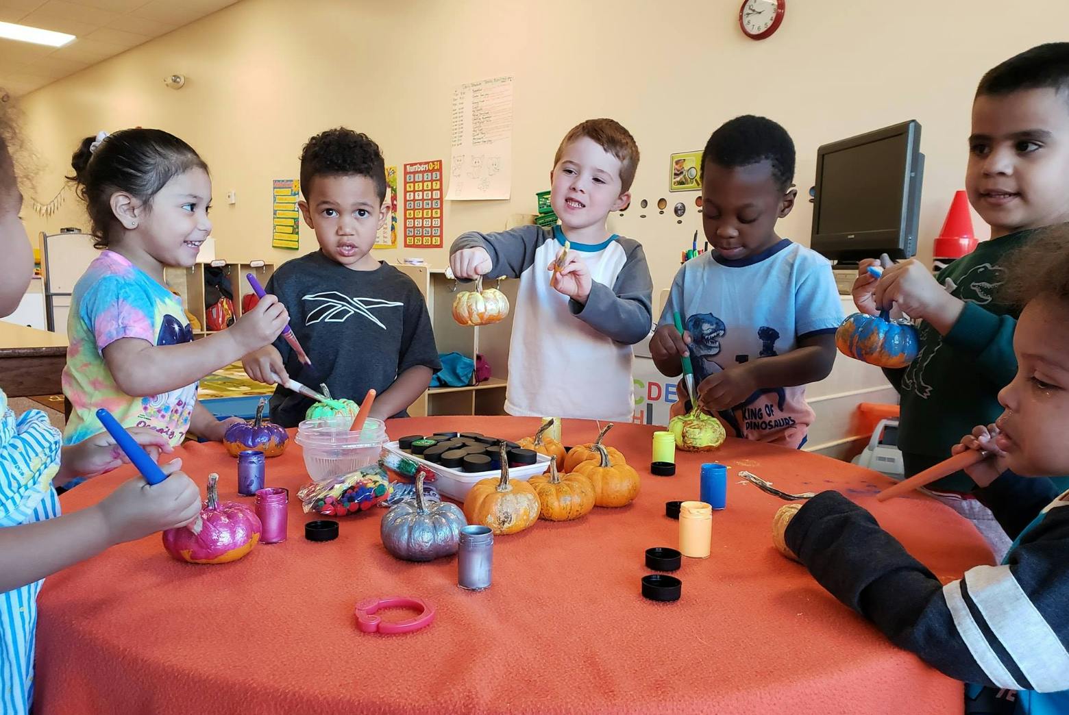 Children painting small pumpkins at a table
