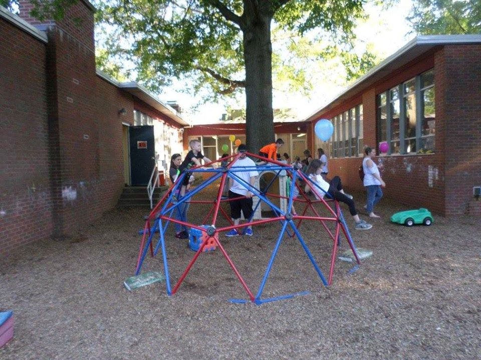 Children playing on a red and blue climbing dome on a playground