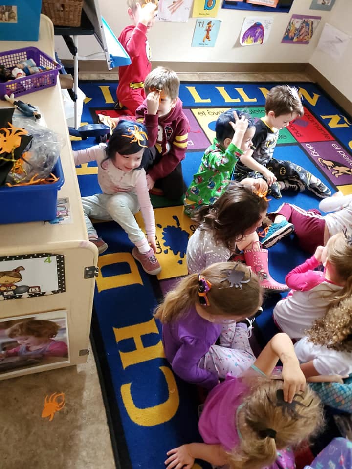 Children sitting on a colorful rug in a classroom