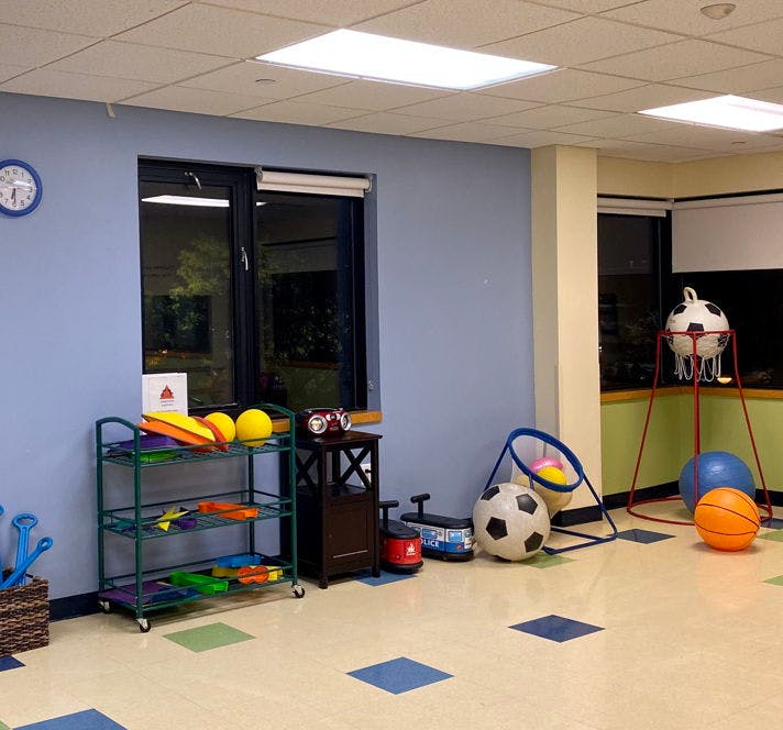 Room with sports equipment, including balls, a soccer goal, and a cart