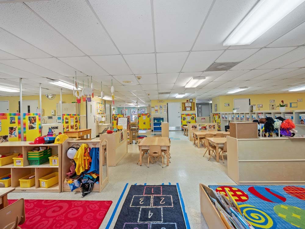 Empty colorful preschool classroom with small tables and chairs
