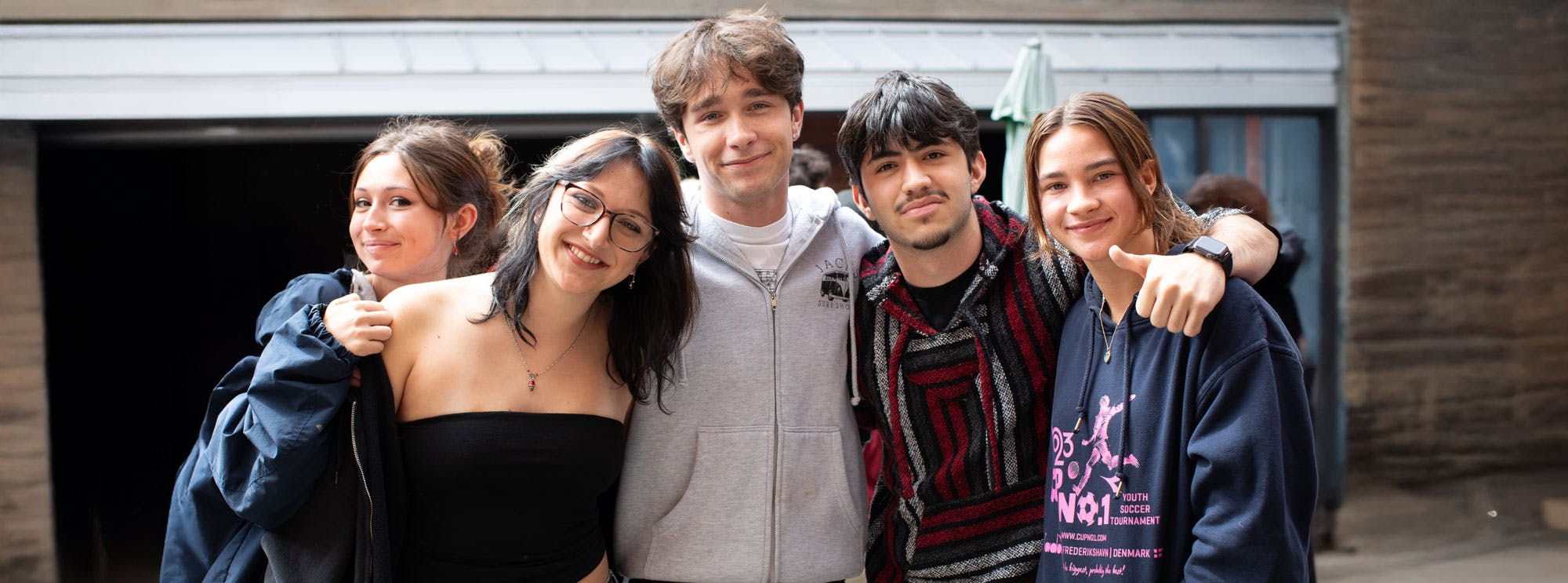 Five people standing close together and smiling at the camera