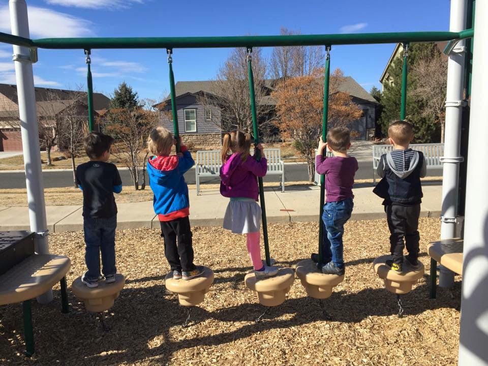 Five children standing on a playground swing set