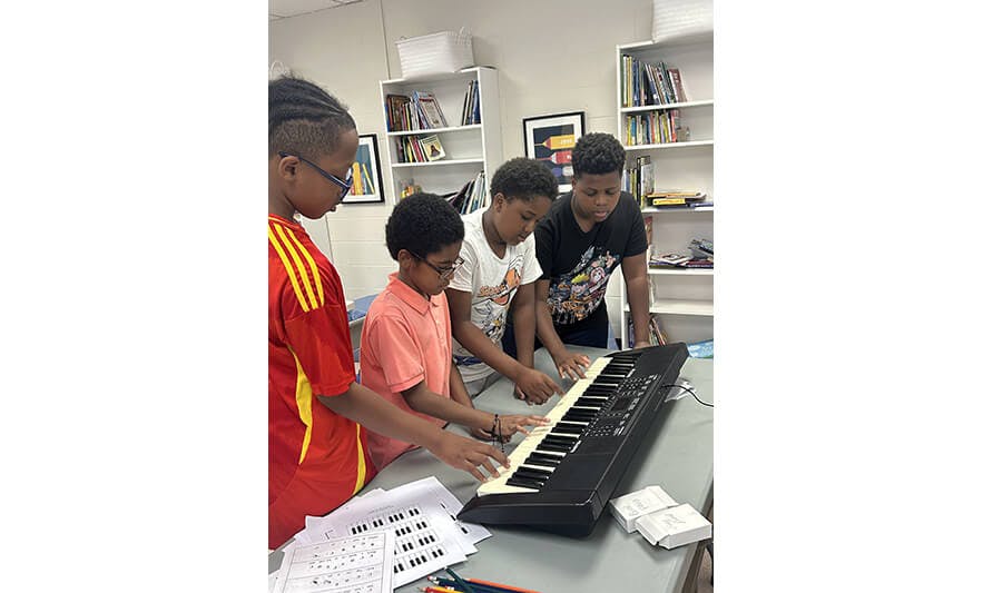 Four children gathered around an electronic keyboard