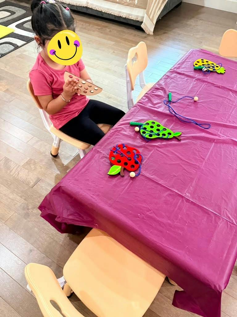 Child sitting at a table with fruit-shaped lacing toys
