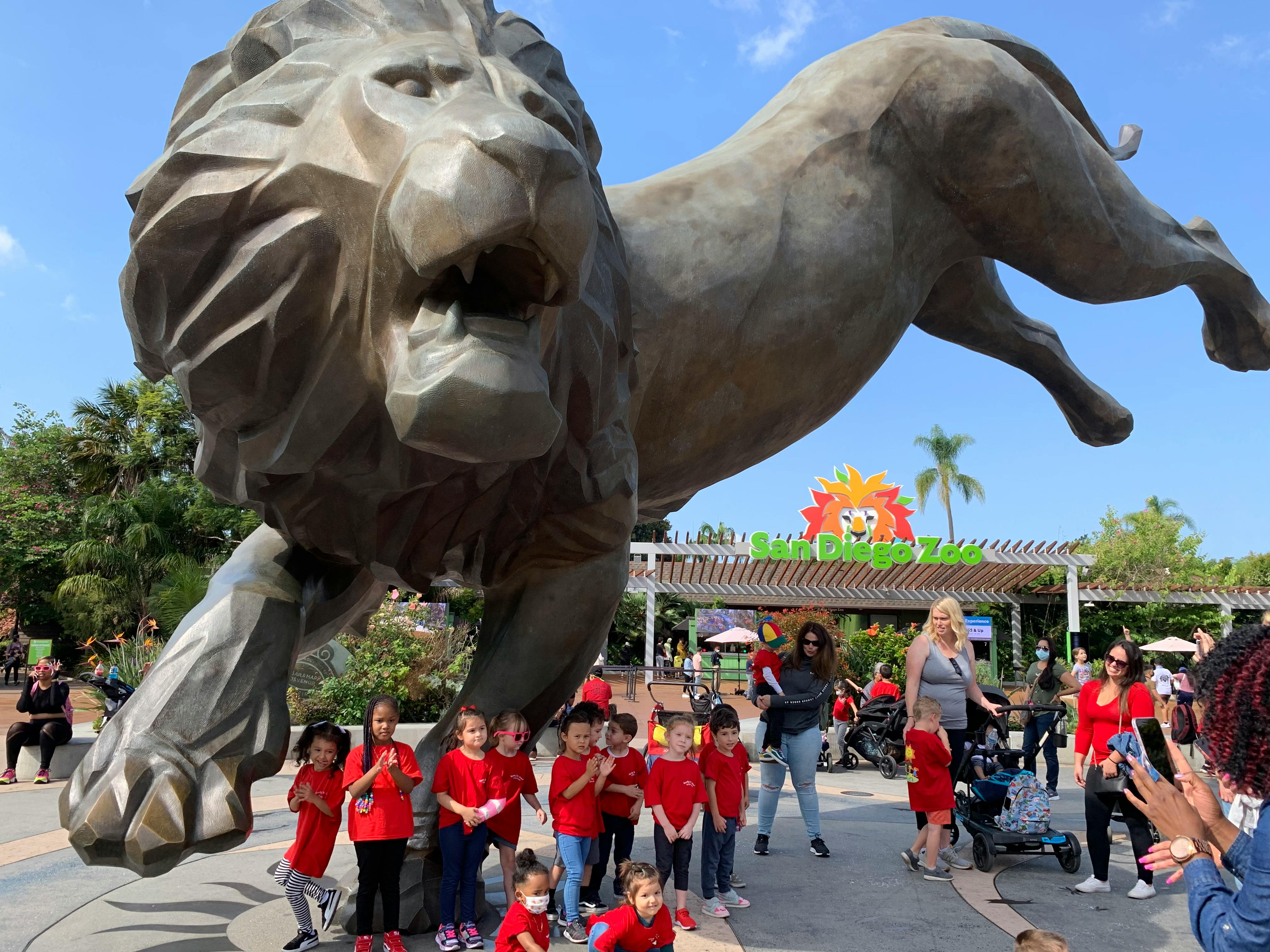 Large lion statue with a group of children in red shirts below it