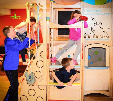 Children playing on an indoor wooden playset