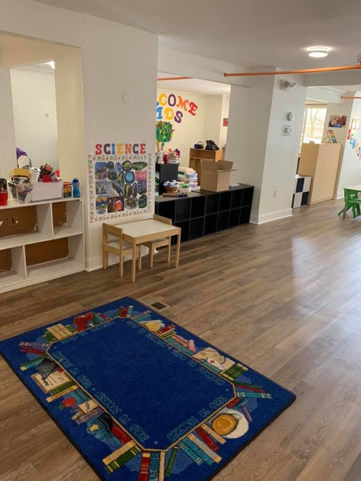 Classroom with a blue rug, small table and chairs, and a science poster