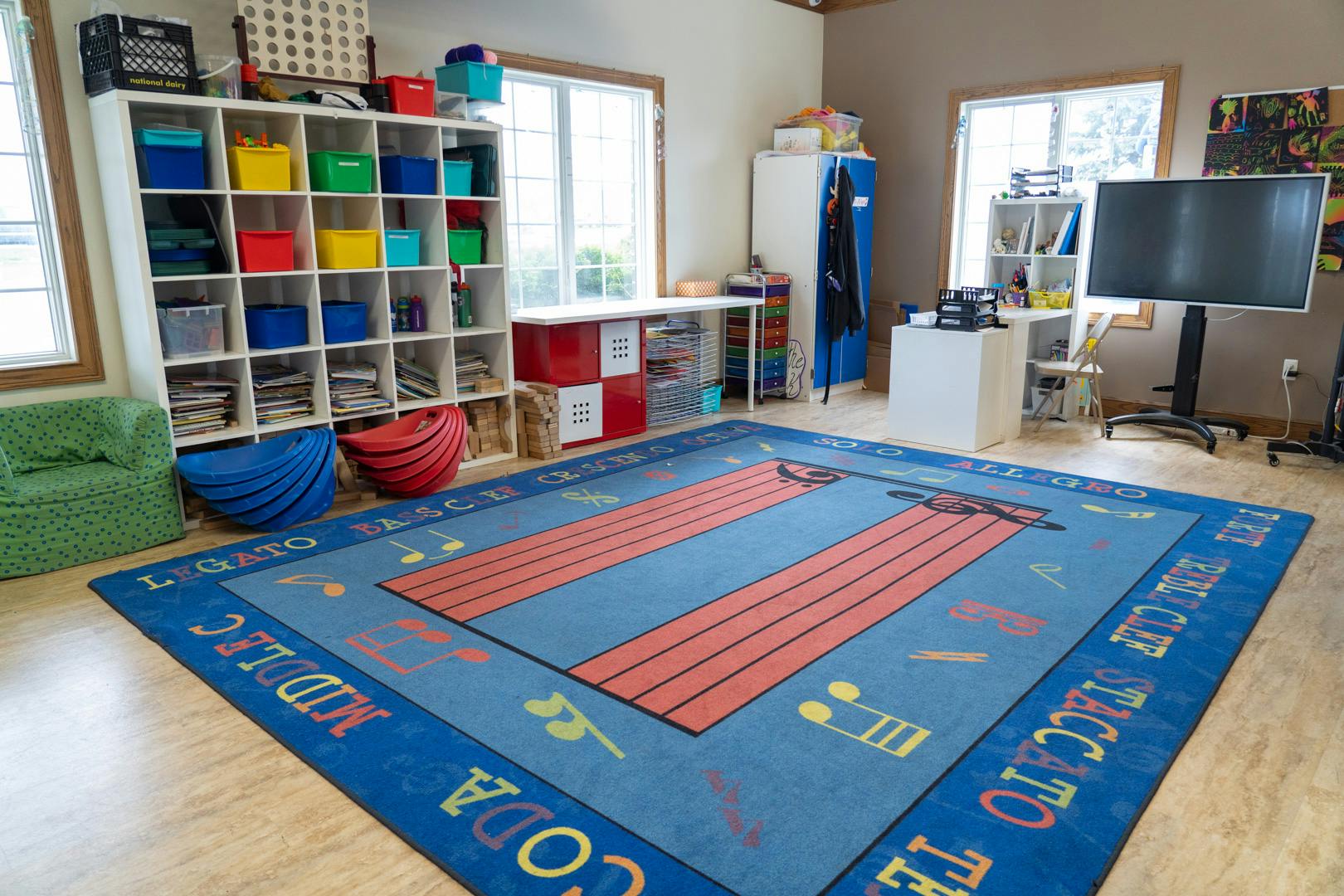 Room with a large blue rug, shelves, and a television