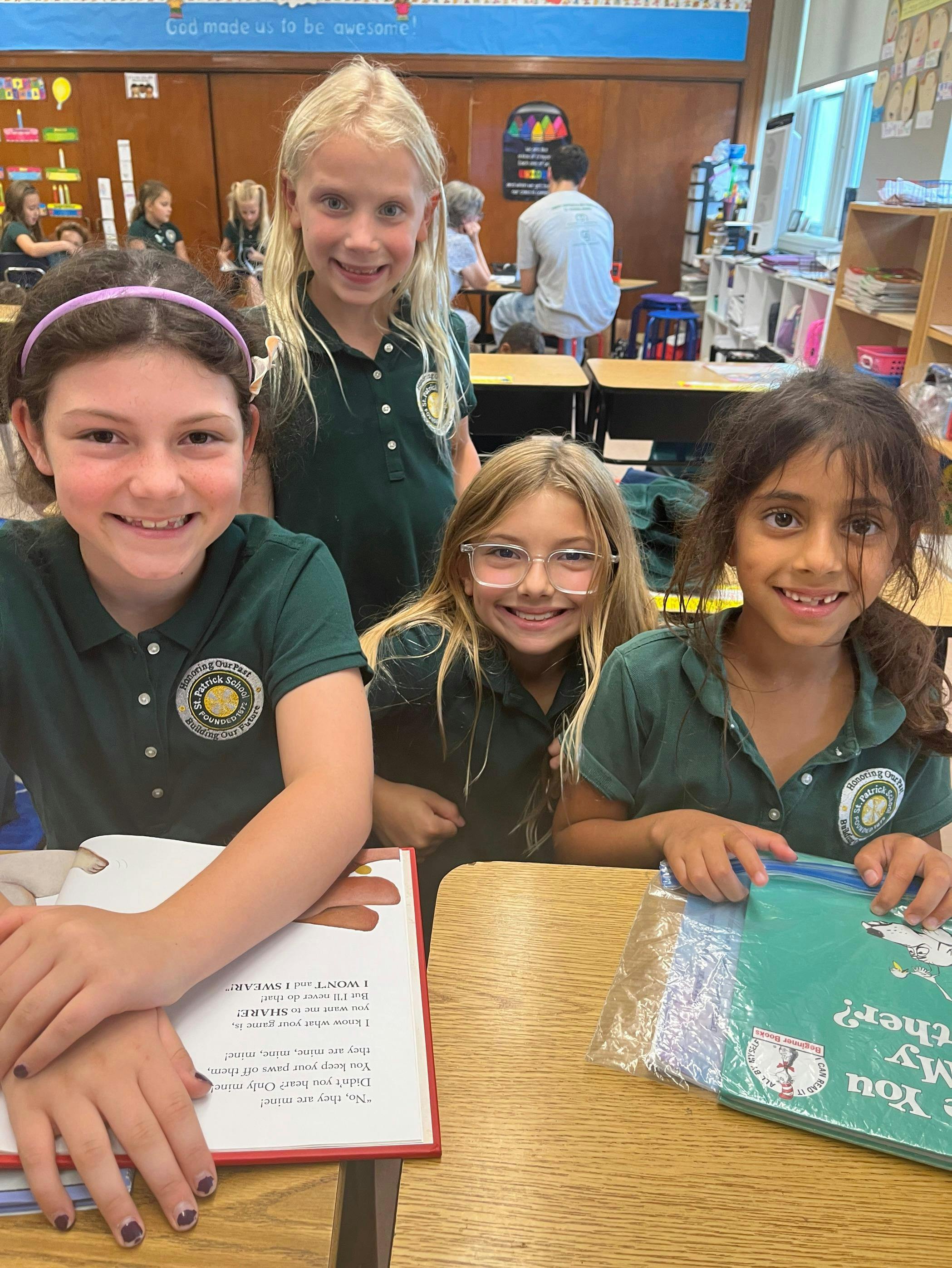 Four children in green shirts in a classroom
