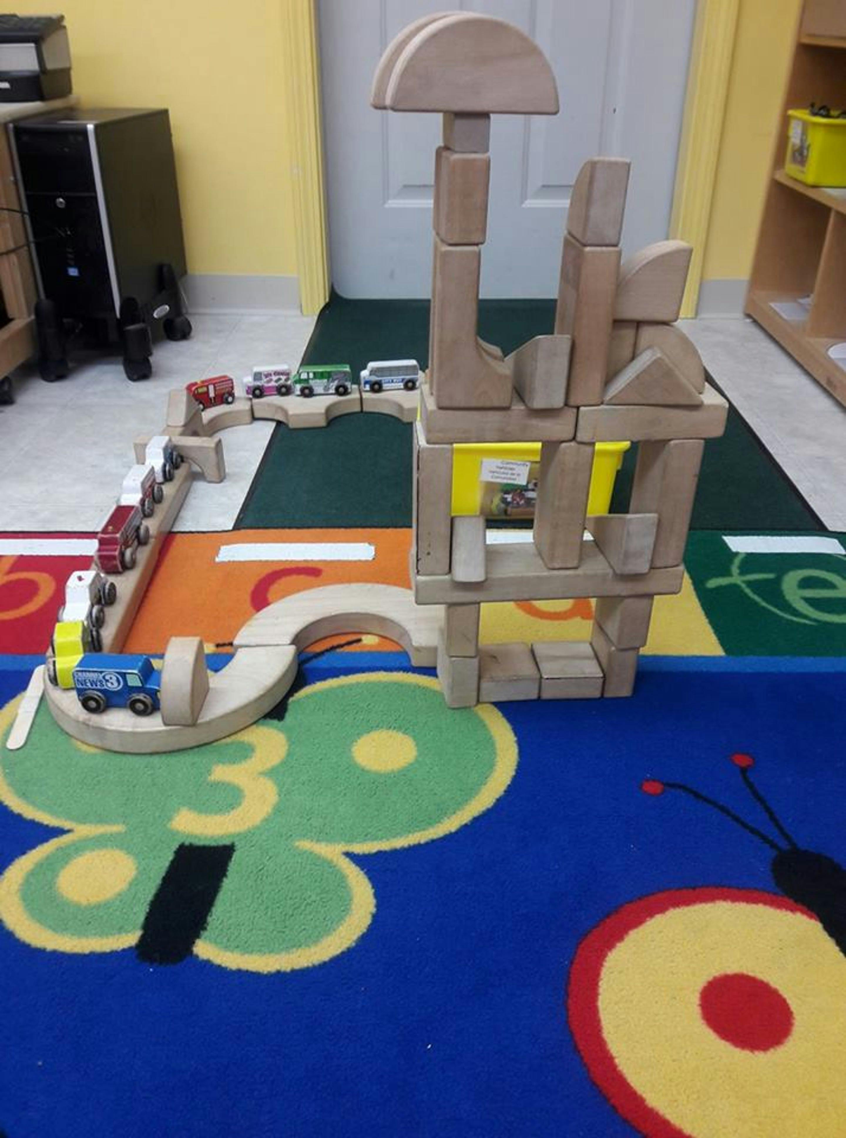 Wooden blocks and toy cars on a colorful rug