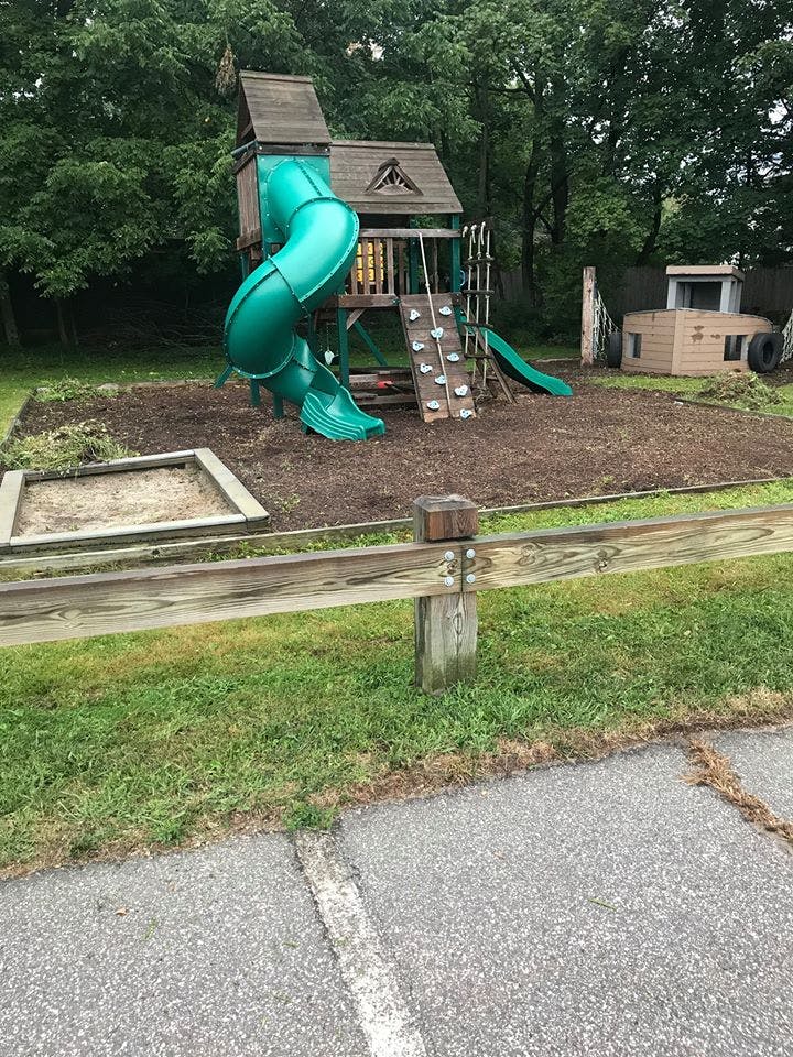 Playground with a wooden structure, green slide, and sandbox