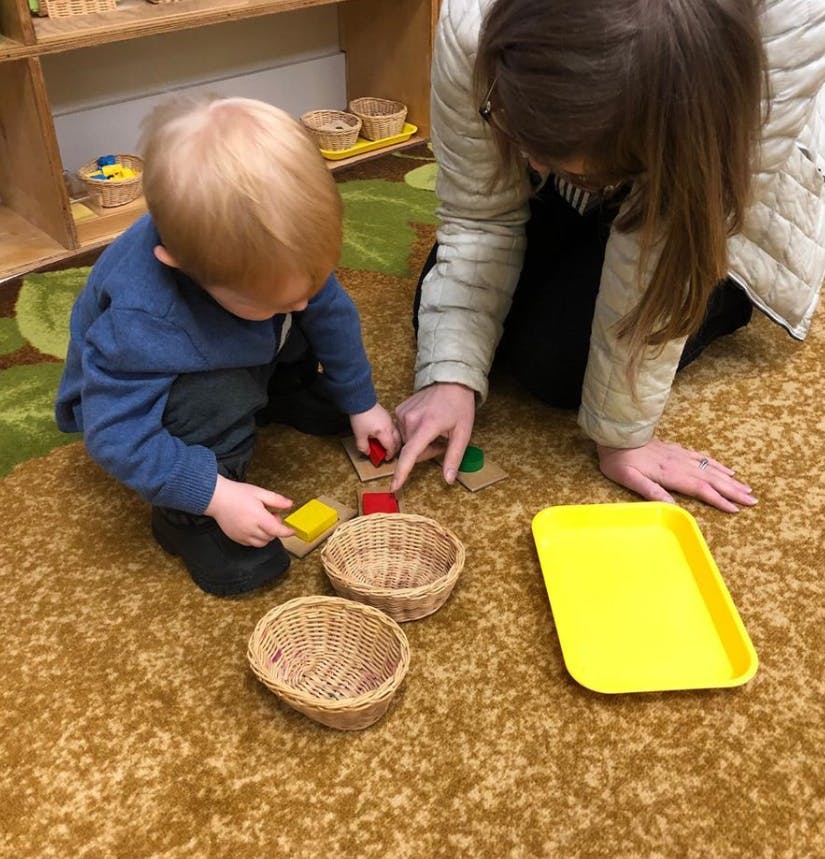 Adult and child on floor playing with blocks and baskets