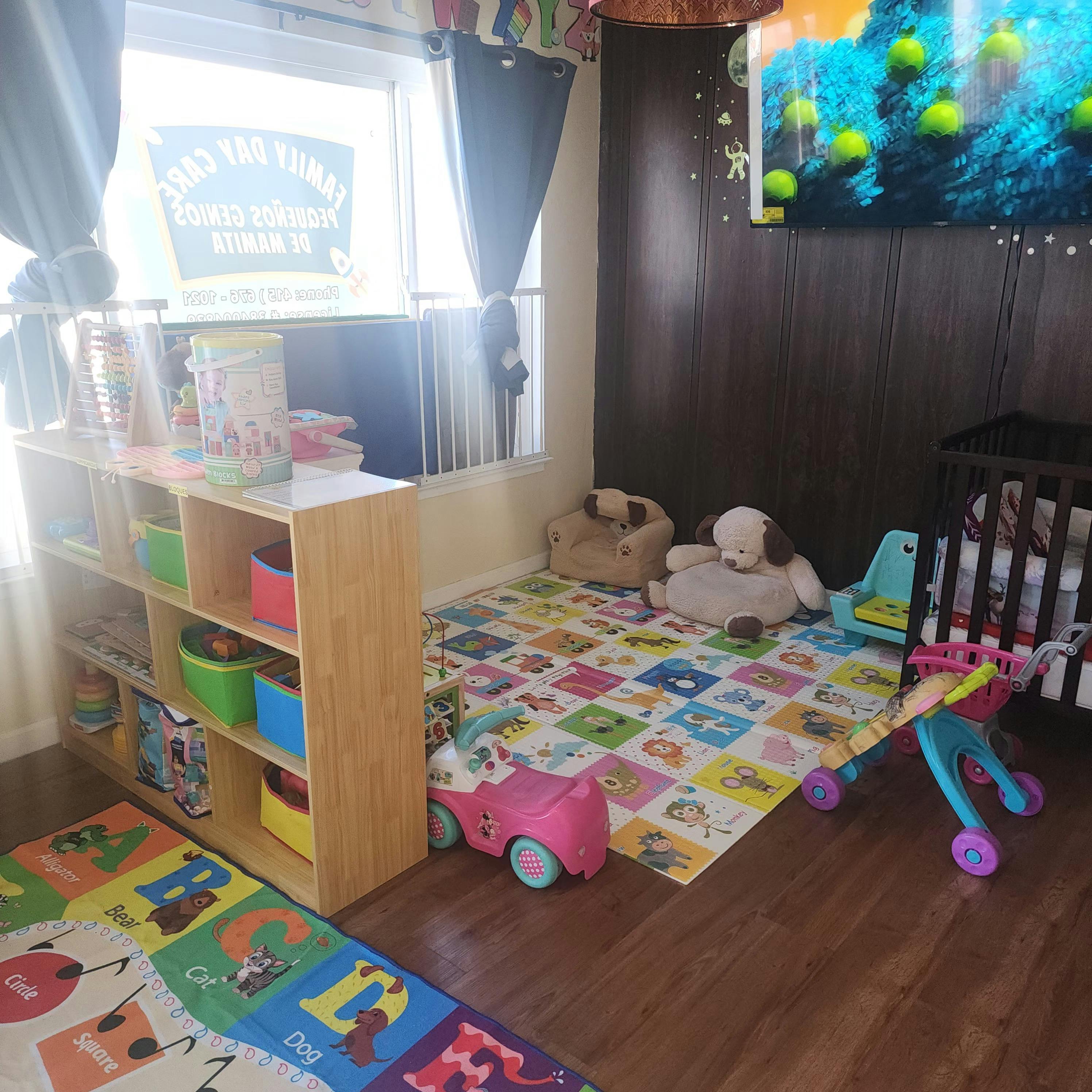 A childcare room with toys, play mats, shelves, and a crib