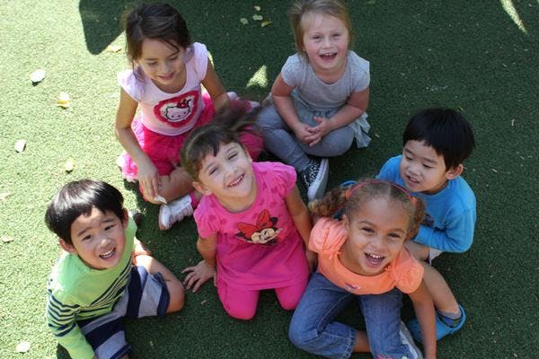 Six children sitting on green ground looking up