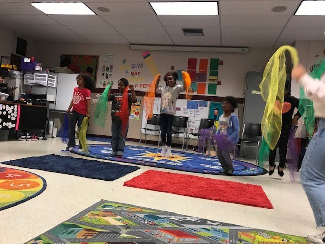 Children in a classroom holding colorful scarves