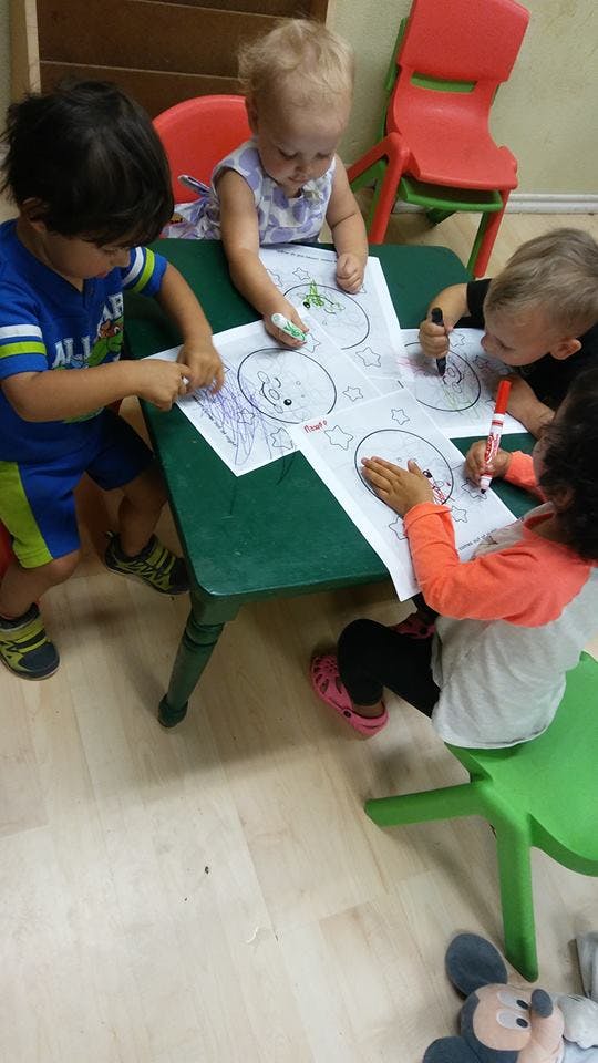 Four children coloring at a green table