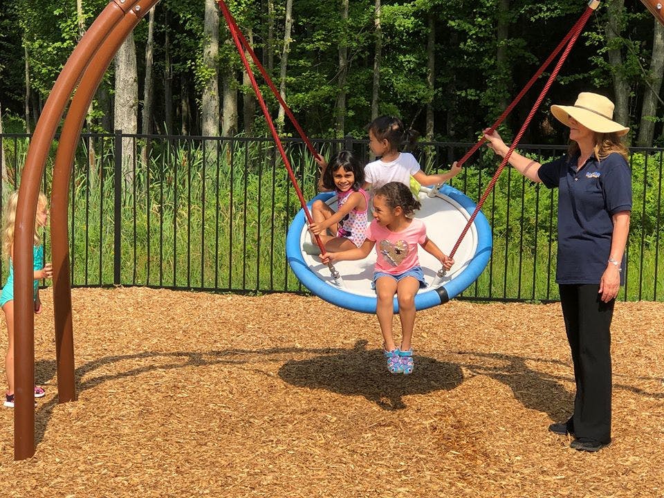 Person pushing children on a large swing on a playground