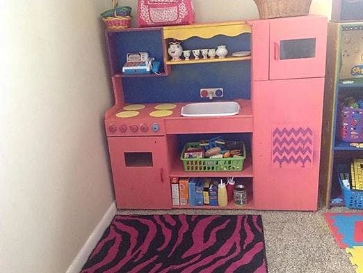 Pink toy kitchen set with a stove, sink, and refrigerator