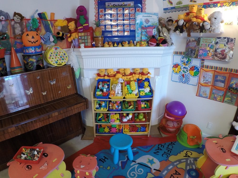 Playroom with a piano, toy shelf, and colorful rug