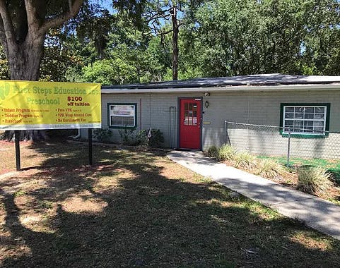 Building with a red door and a yellow sign for "First Steps Education"