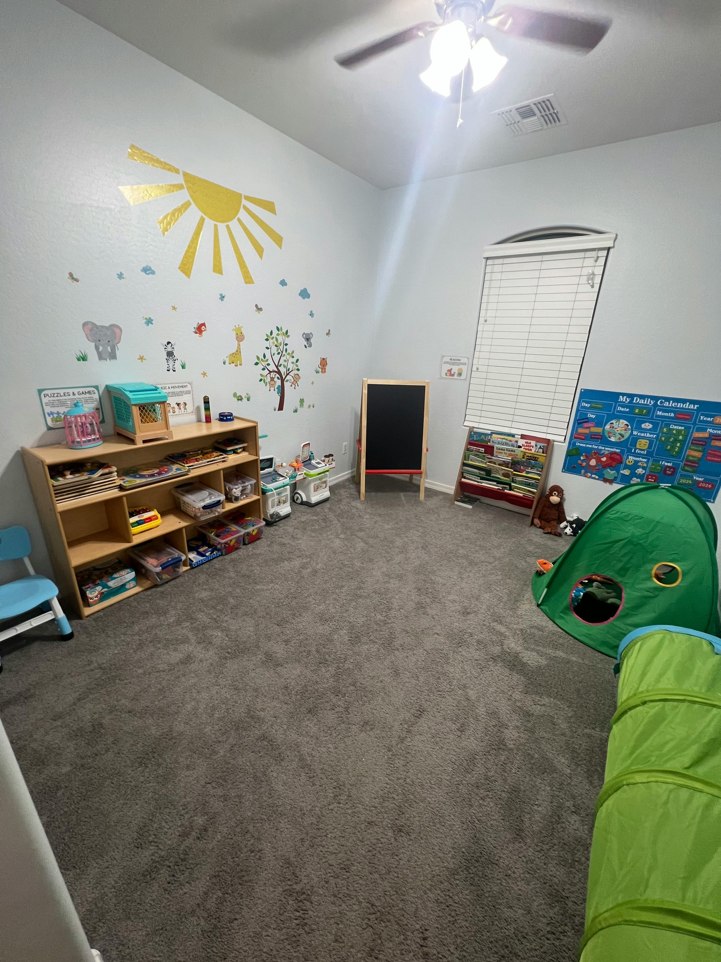Children's playroom with a bookshelf, chalkboard, and play tent