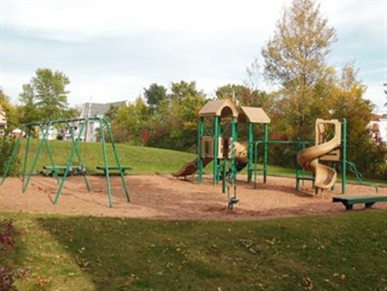 Empty playground with swings, slides, and climbing structures on sand