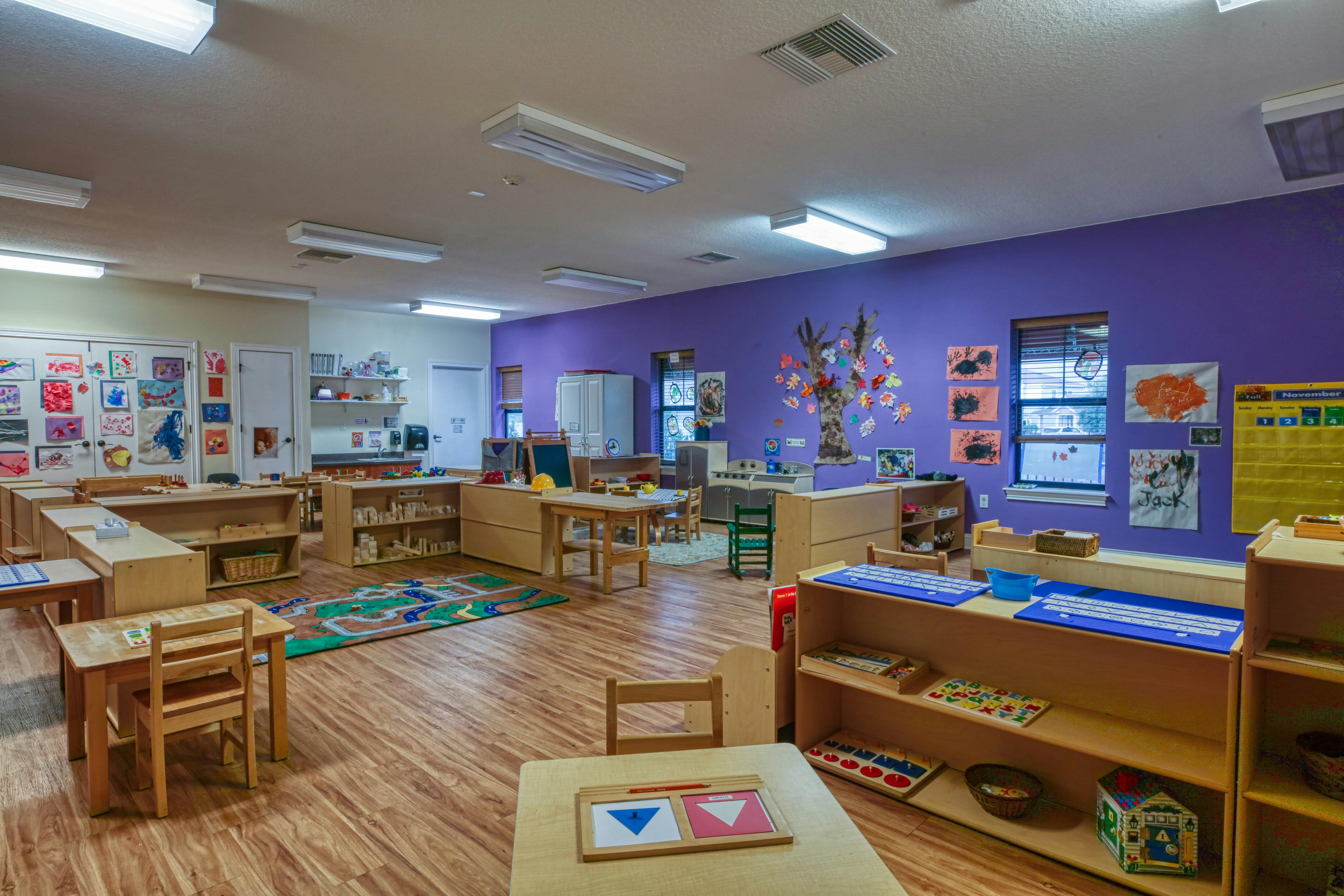 A colorful classroom with various learning stations, wooden tables, and chairs