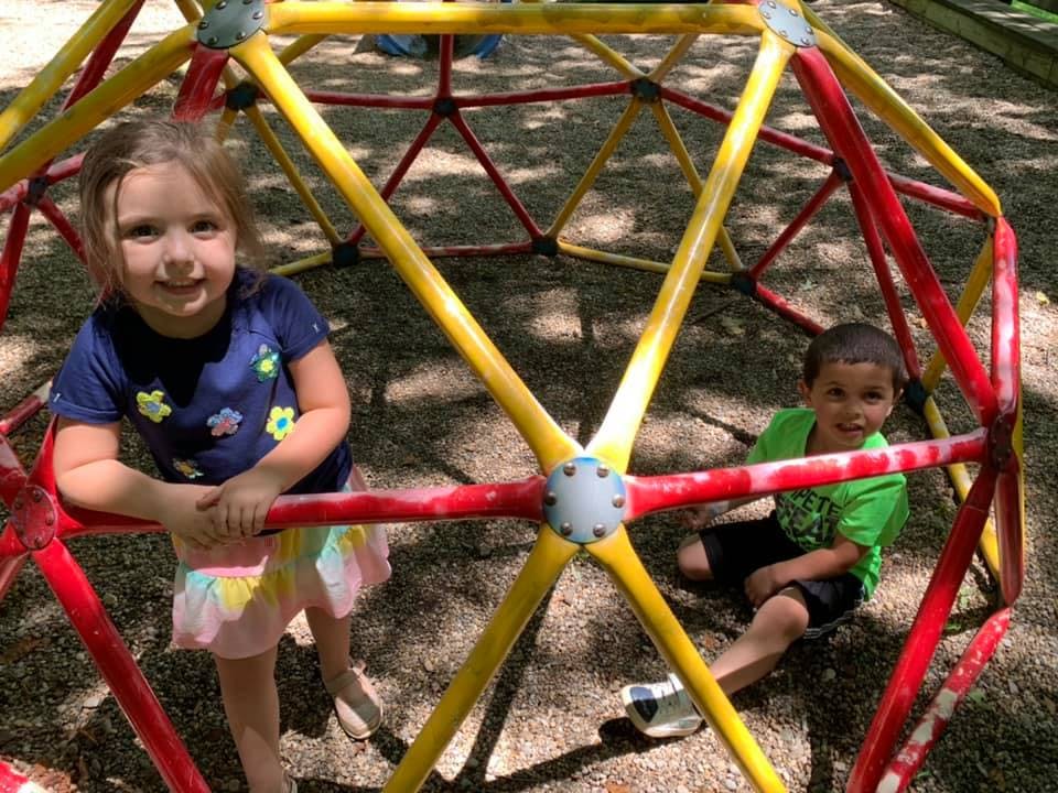 Two children on a playground climbing dome