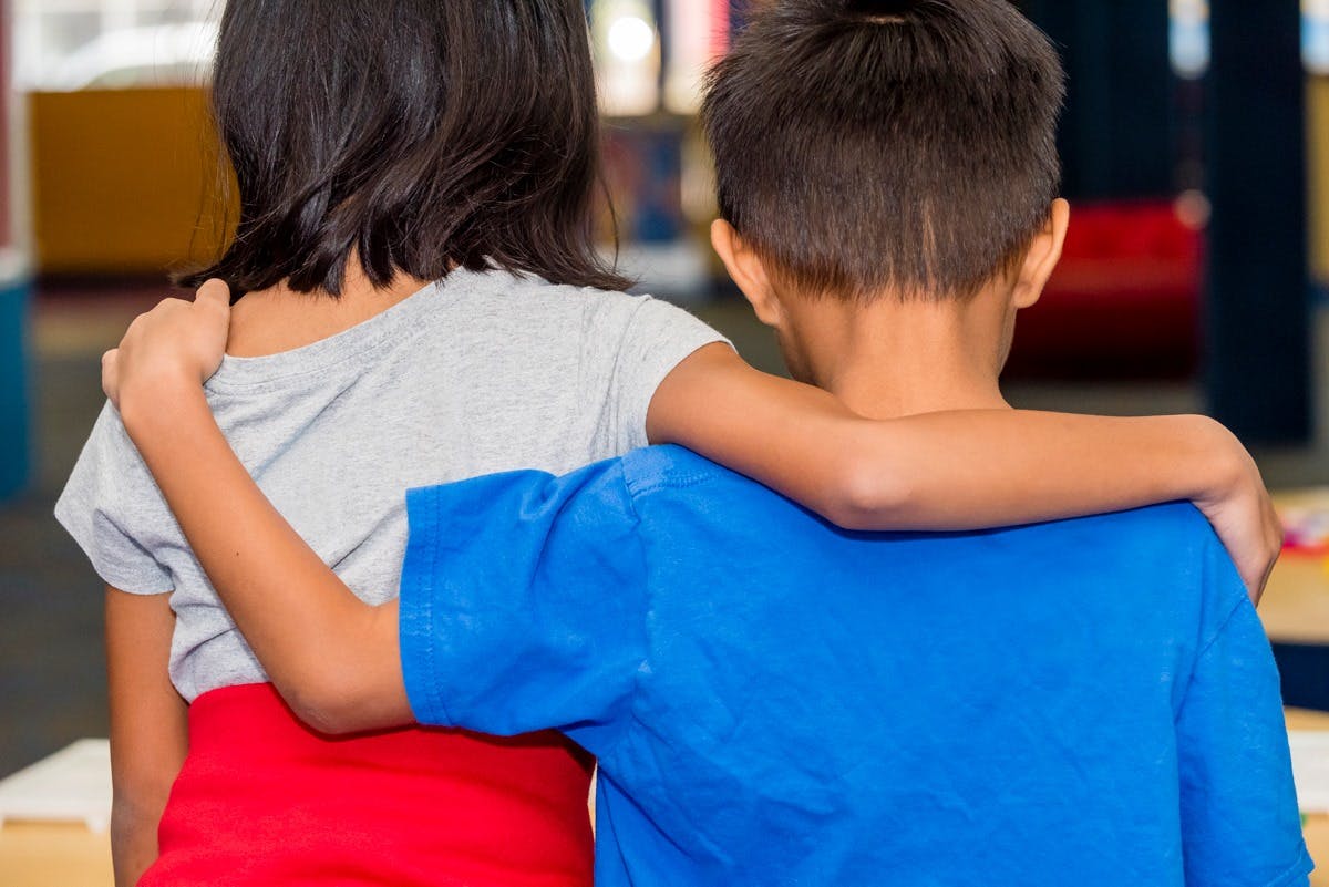 Two children with arms around each other's shoulders