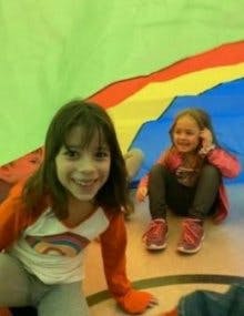 Two children playing under a colorful parachute
