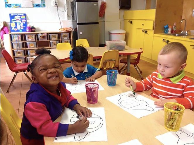 Three children drawing at a table