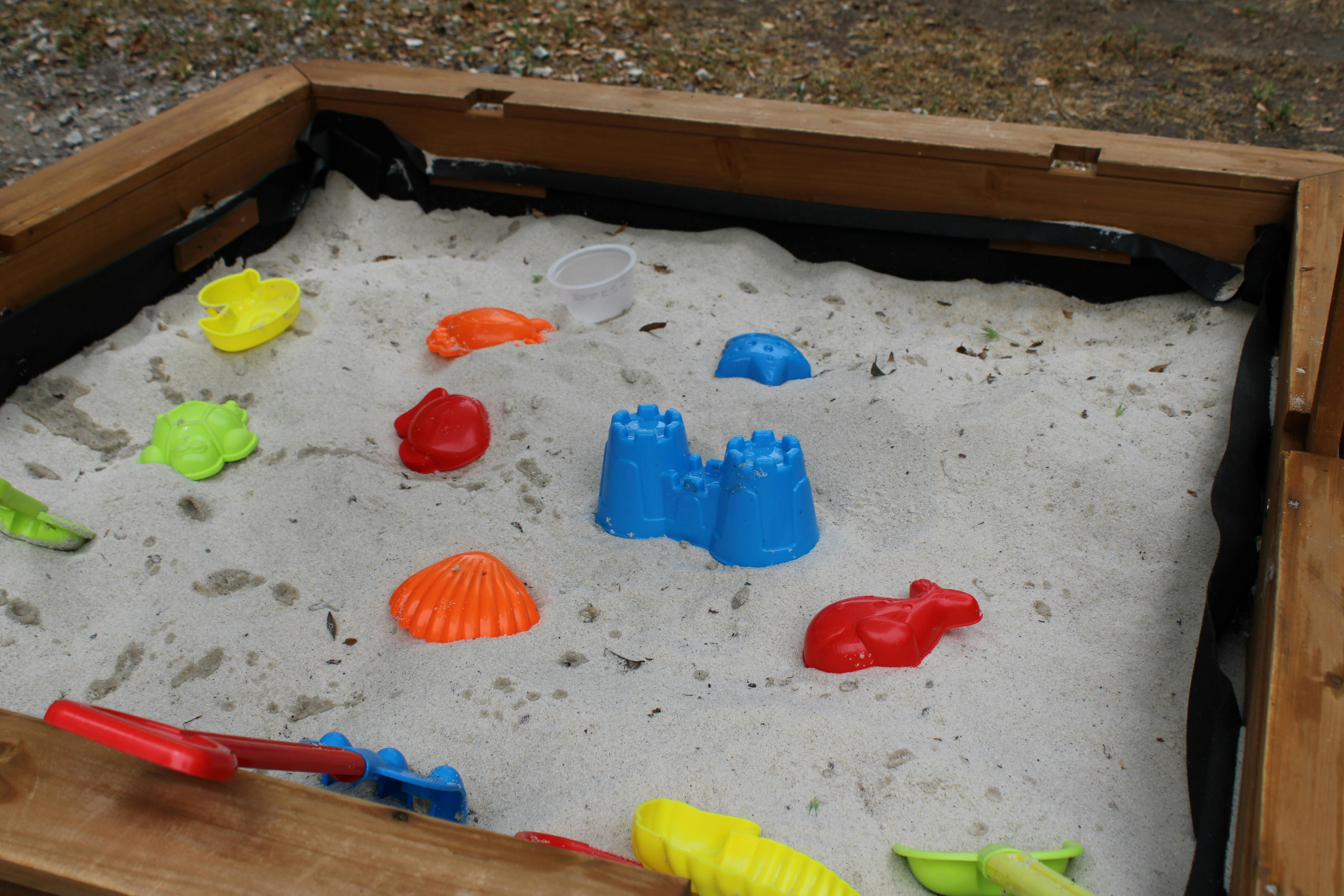 Sandpit with colorful sand toys including a blue sandcastle mold