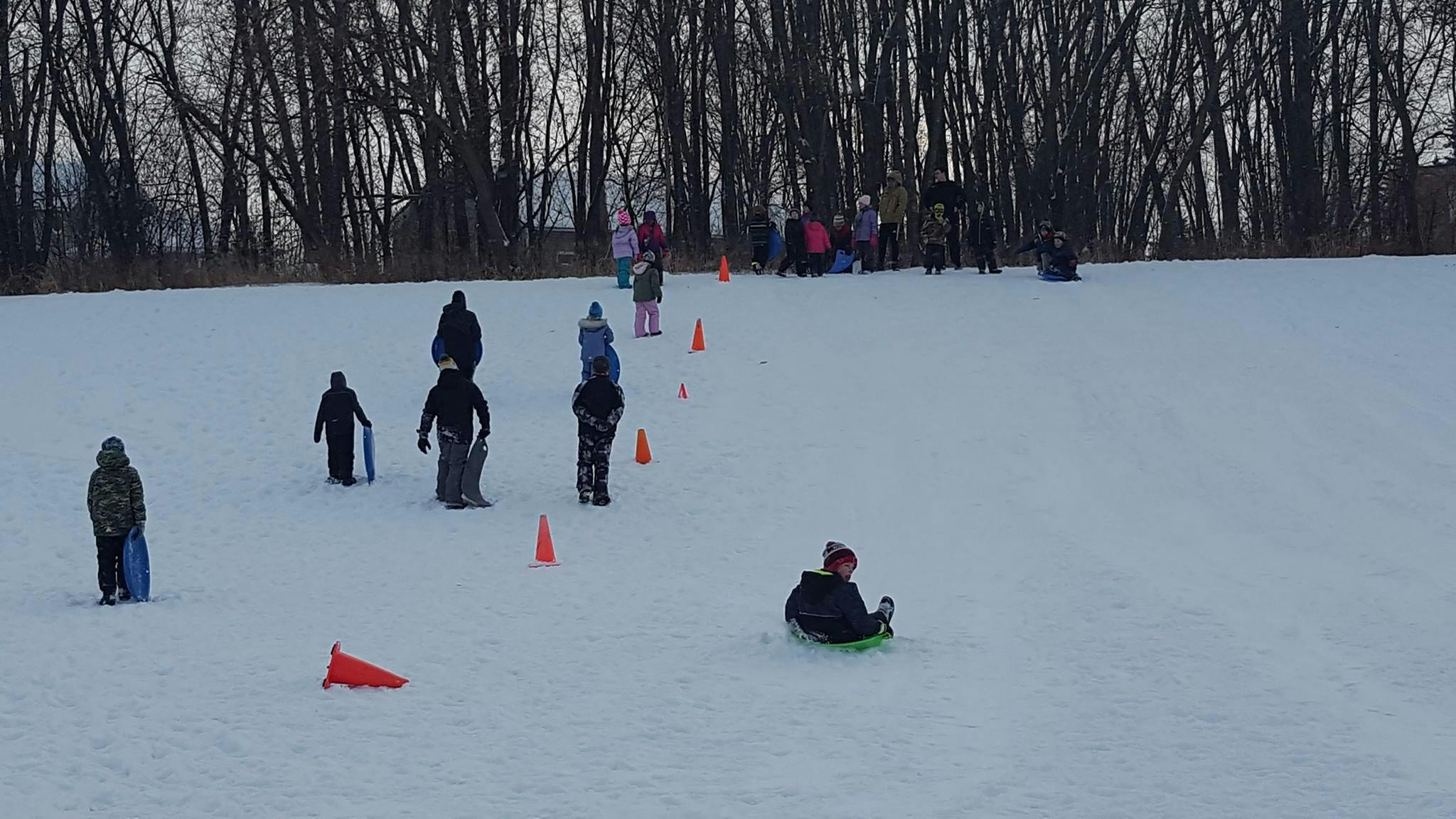 People sledding down a snowy hill