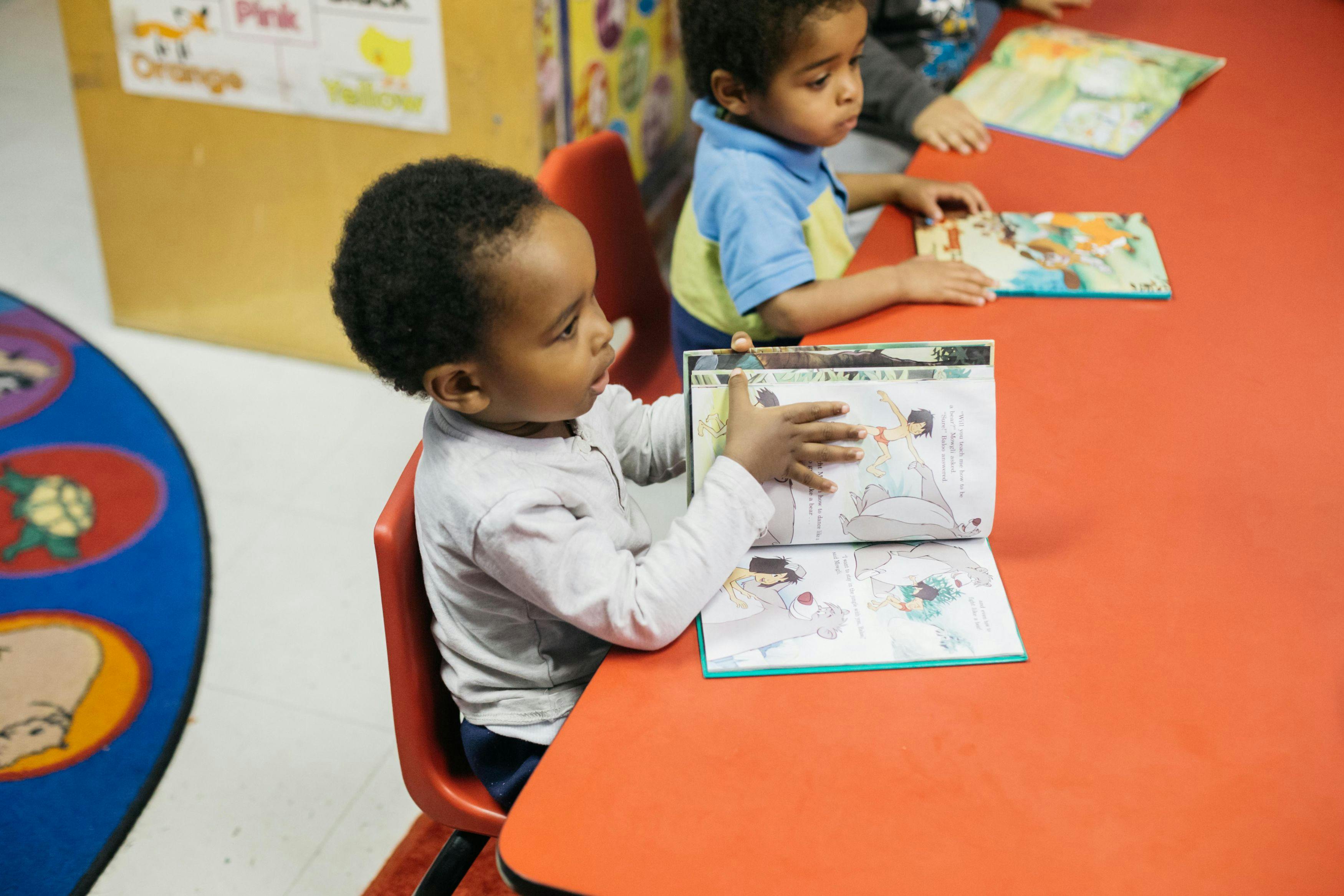 Child sitting at a table, looking at a book
