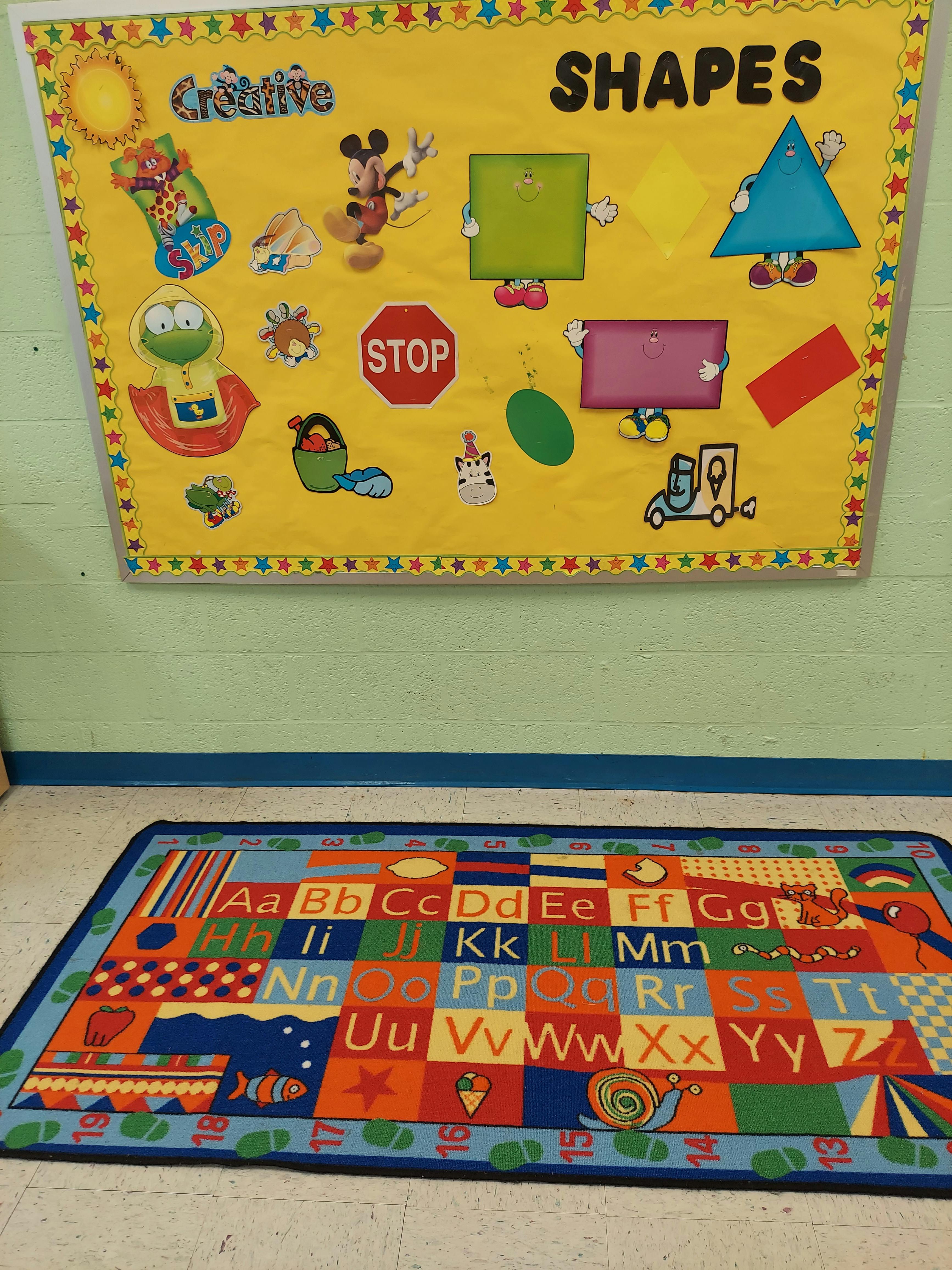 Classroom with a shapes bulletin board and an alphabet rug