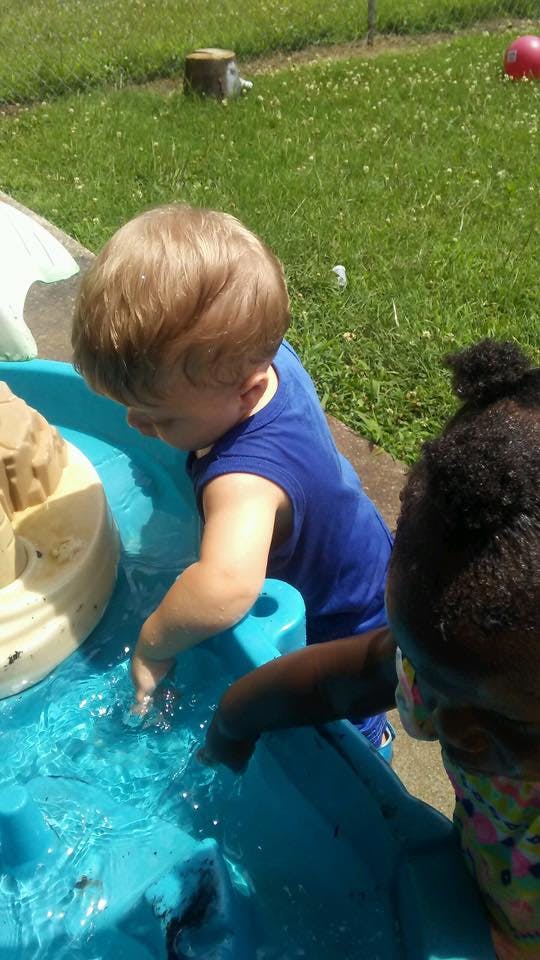 Child in blue shirt playing in a water table