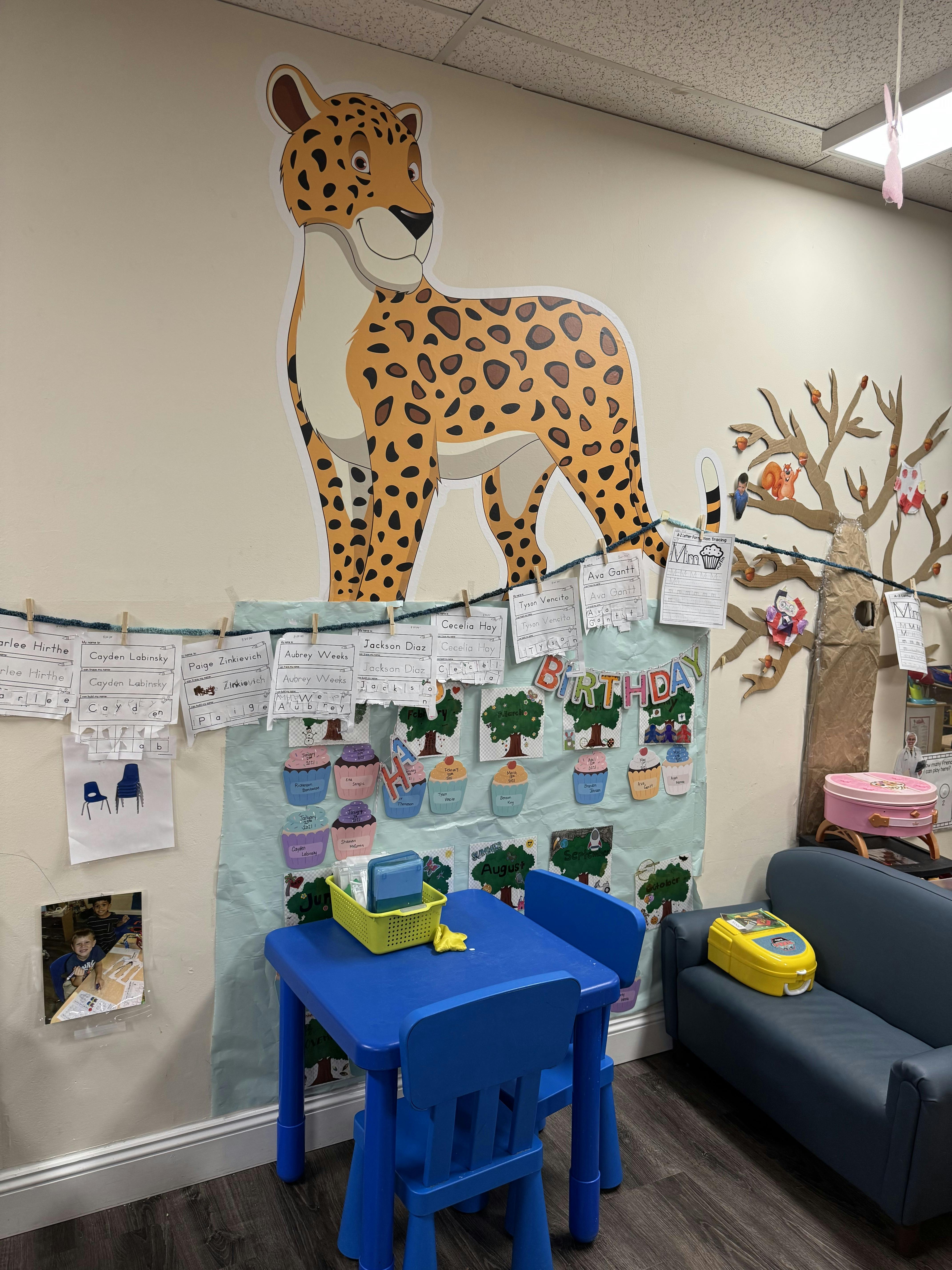 Classroom wall with a large cheetah cutout above a small blue table and chairs
