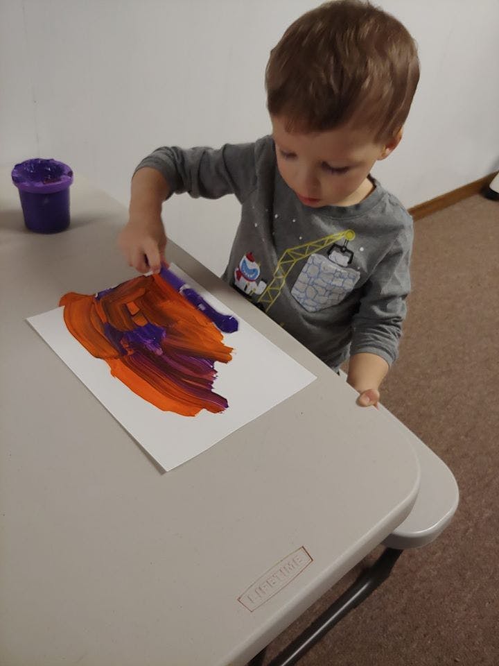 Child painting with fingers on paper at a table
